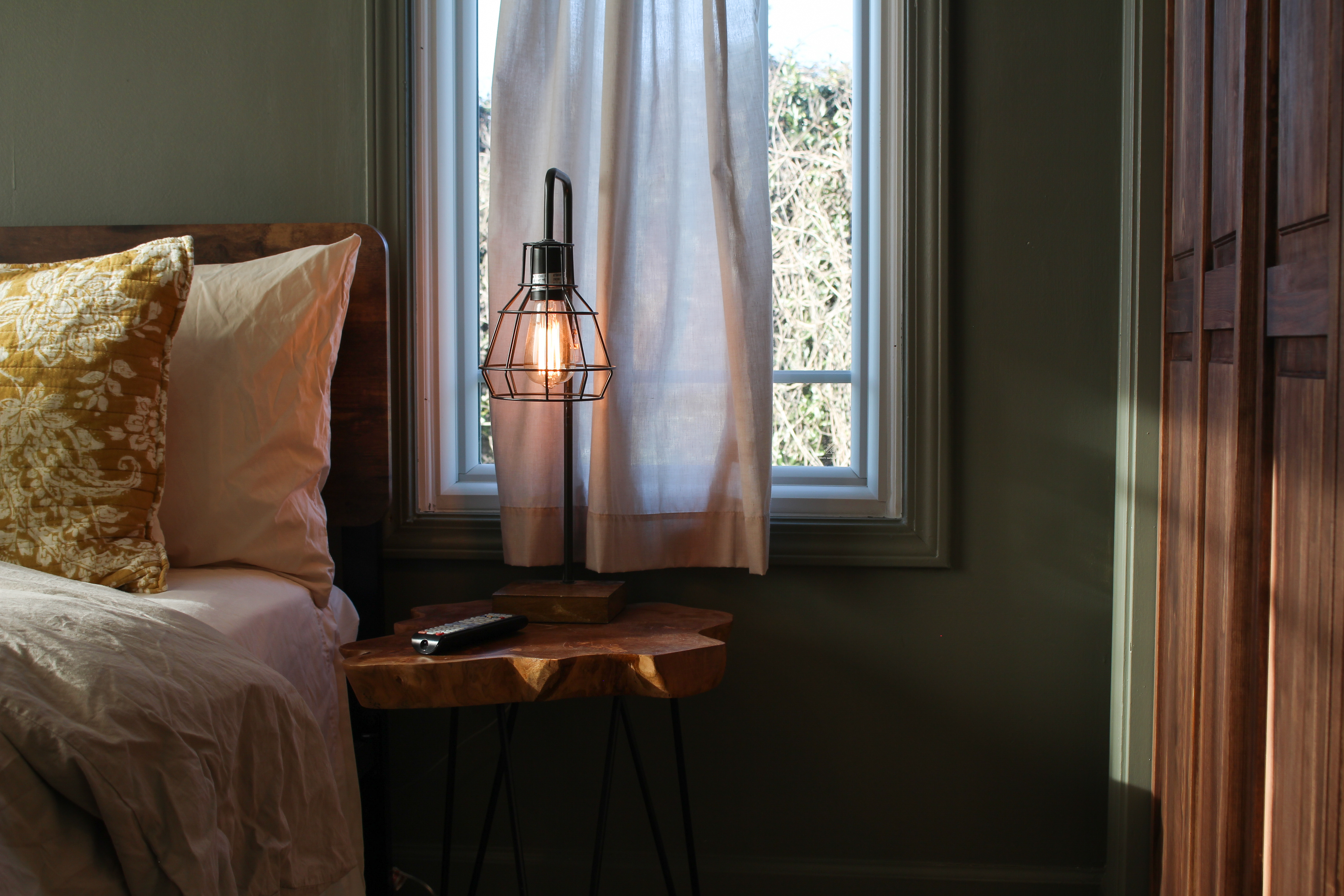 Bedroom nightstand with caged Edison lamp in warm evening light